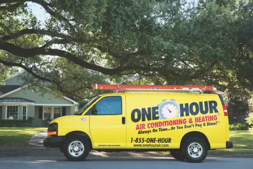 One Hour Air Conditioning & Heating yellow service van parked in front of a residential home under a tree.